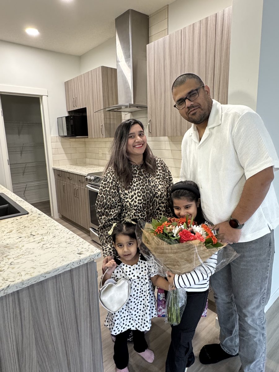 A family of four with flowers in the kitchen of their new home