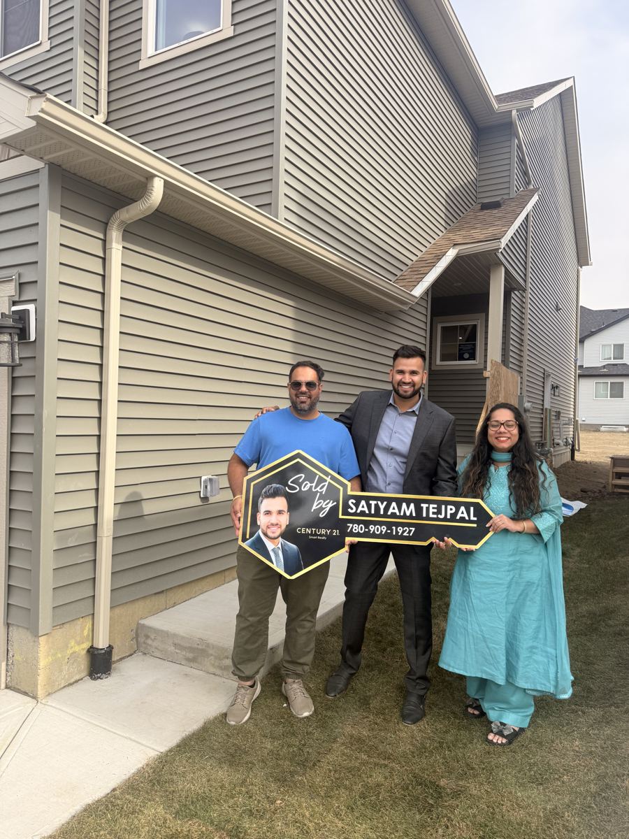 Satyam Tejpal with two clients holding a Sold key sign beside their new home