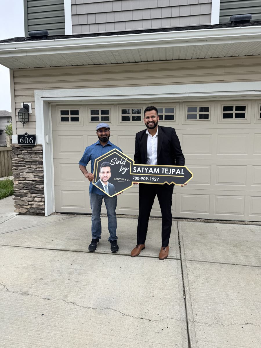 Satyam Tejpal and a client holding a Sold key sign in front of a double garage