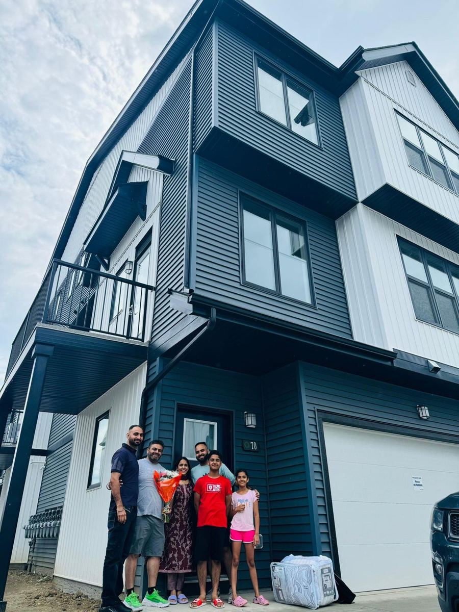 A family of six with Satyam Tejpal and flowers outside their new three-storey home